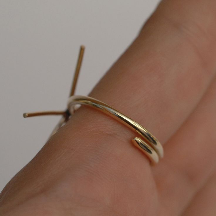 a person's hand wearing a gold ring with two thin rings on the middle