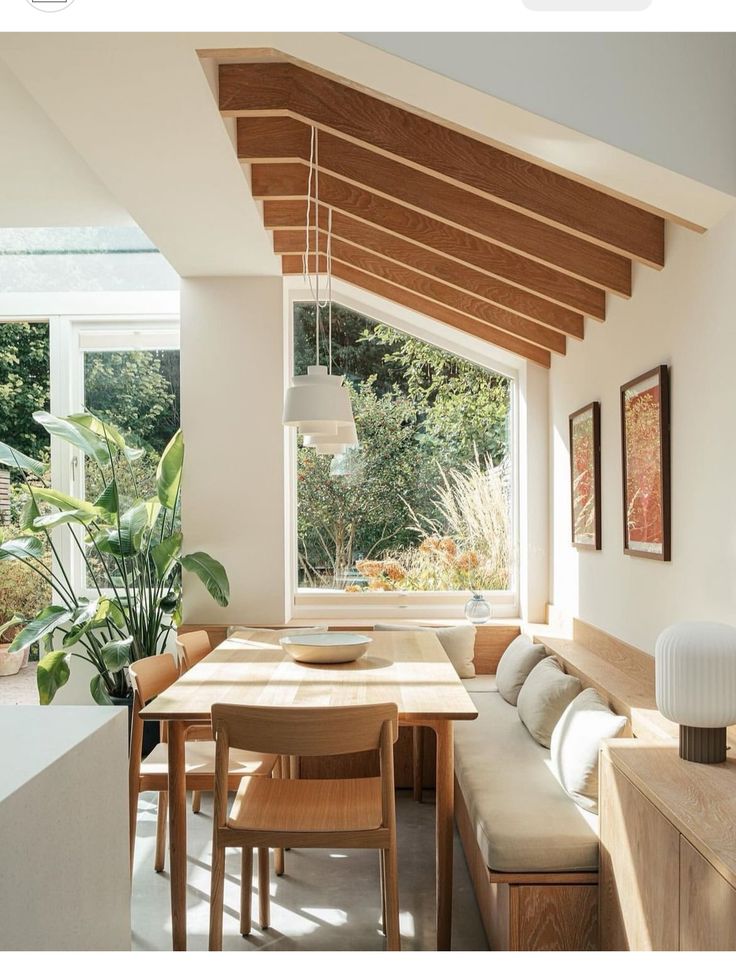 a dining room table and bench in front of a large window with wooden slats