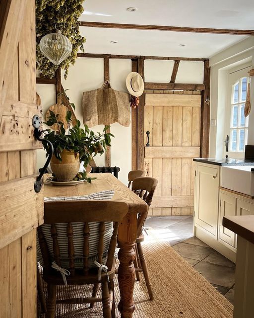 an old fashioned kitchen with wooden chairs and plants on the table in front of it