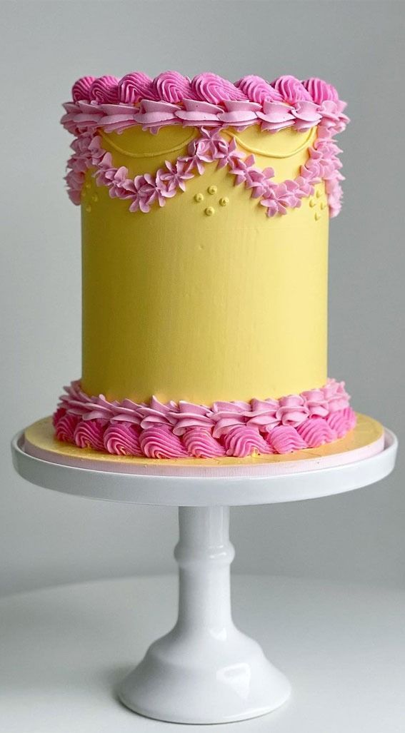 a yellow and pink cake on a white pedestal