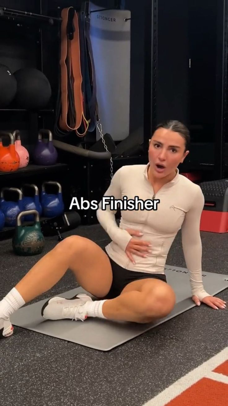 a woman sitting on top of a mat in a gym