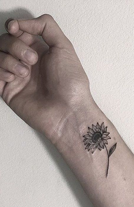 a small sunflower tattoo on the left arm and wrist is shown in black ink