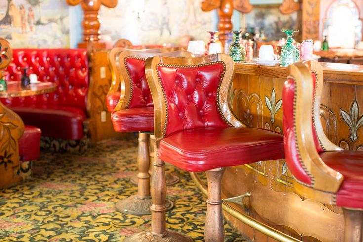 red leather chairs are lined up in a fancy restaurant with gold trimmings and ornate woodwork