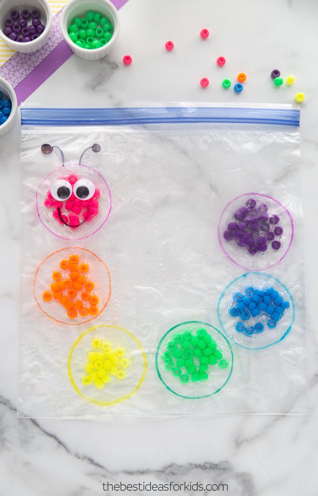 a bag filled with plastic beads next to two cups and spoons on top of a marble table