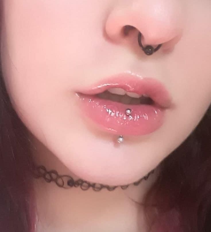 a close up of a woman with piercings on her nose and lip ring in front of her face