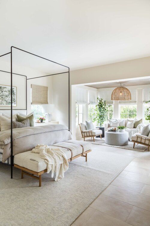 a bedroom with white walls and carpeted flooring has a four poster bed in the middle