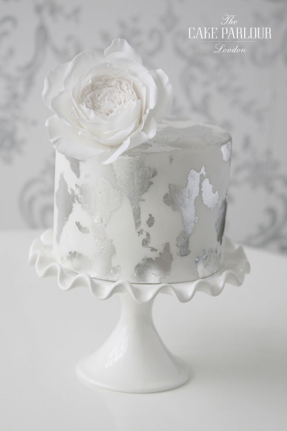 a cake with white frosting and a flower on top is sitting on a table