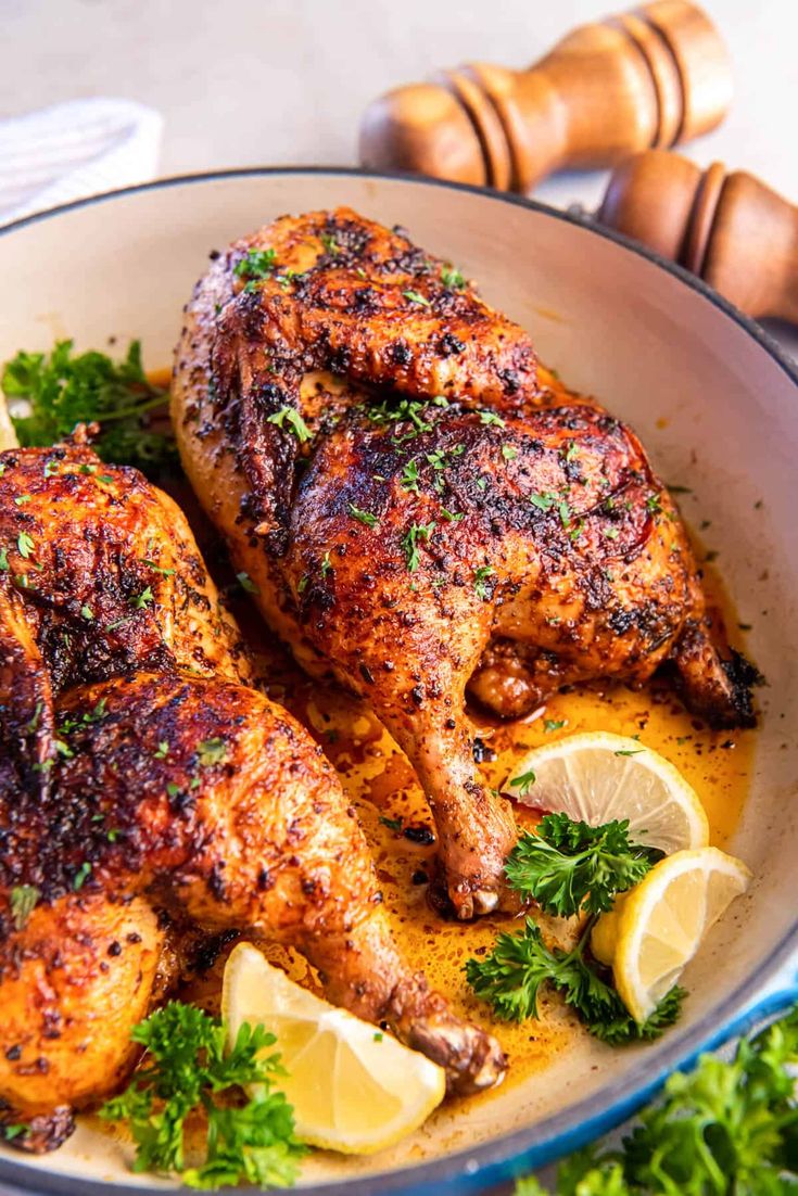 two pieces of chicken in a pan with lemons and parsley