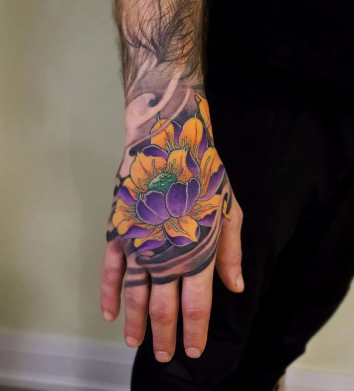 a man's hand with tattoos on it and an orange flower in the middle