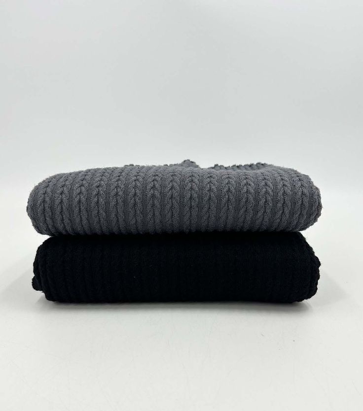 two black and grey blankets stacked on top of each other in front of a white background