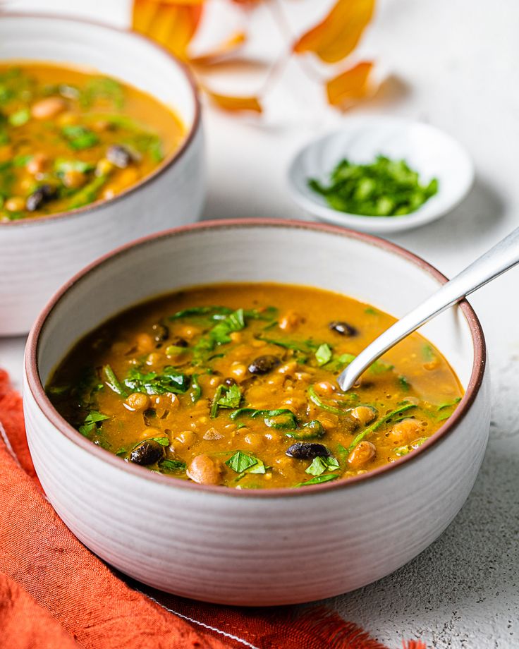 two white bowls filled with soup on top of a table