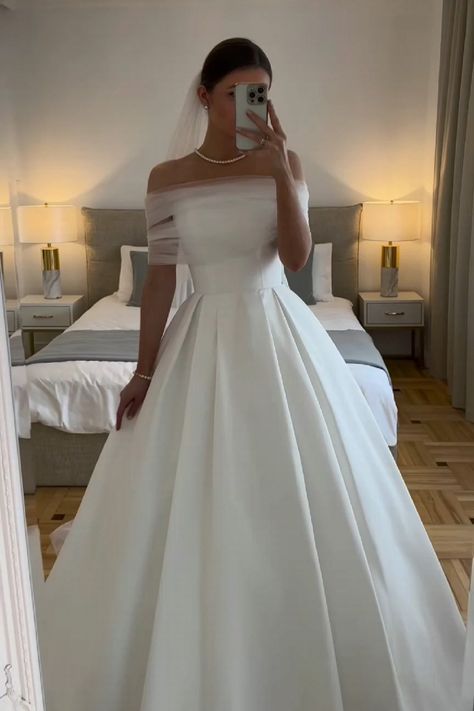 a woman in a white wedding dress taking a selfie with her cell phone and looking into the mirror