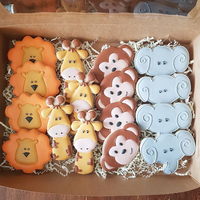 a box filled with lots of decorated cookies in different shapes and colors on top of a wooden table