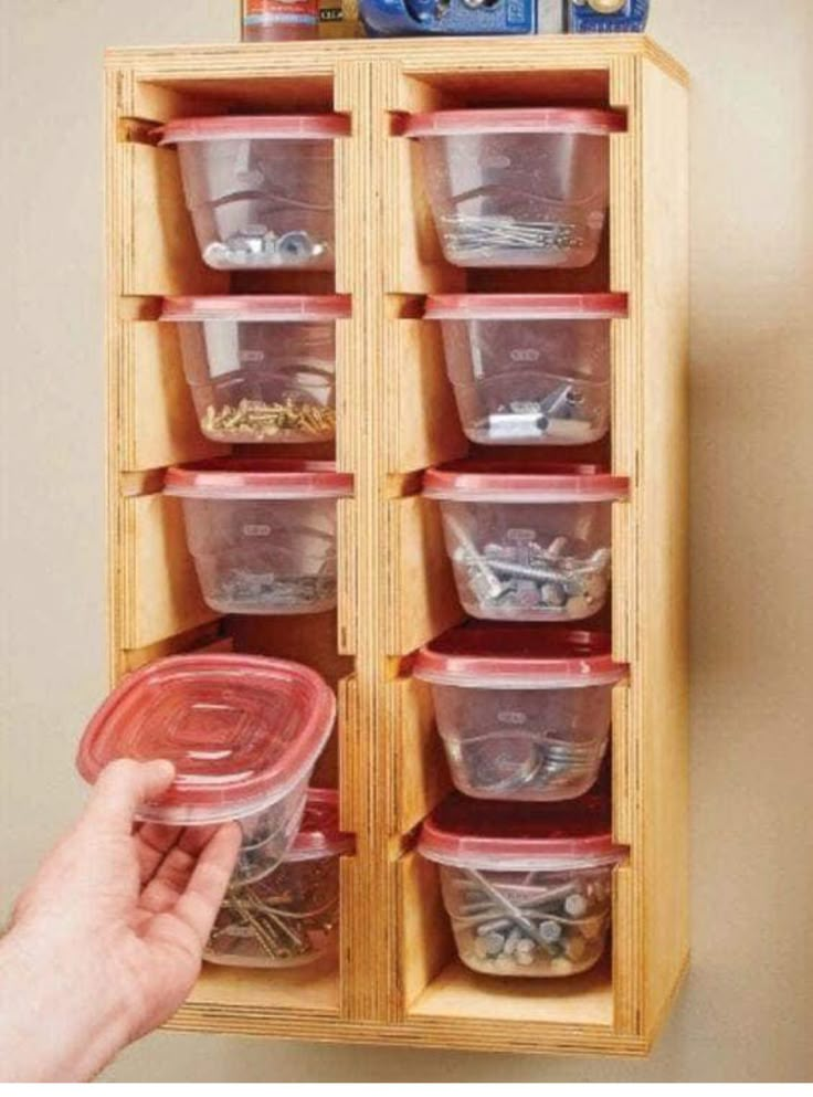 a person holding a plastic container in front of a wooden cabinet with many containers on it