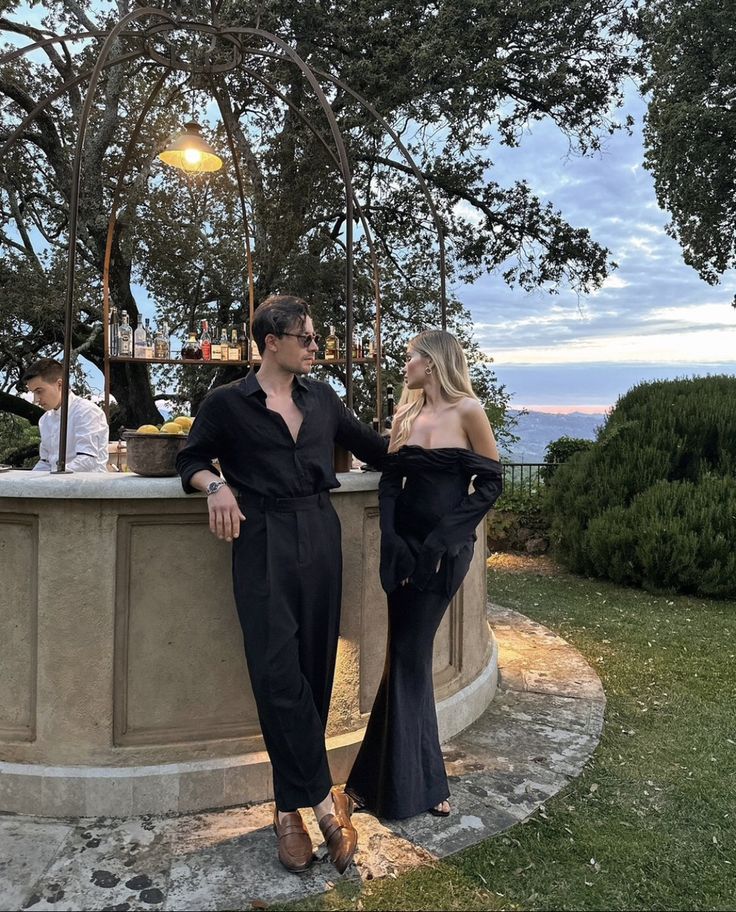 two women standing next to each other in front of a fountain