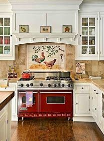 a red stove top oven sitting inside of a kitchen next to white cabinets and counter tops