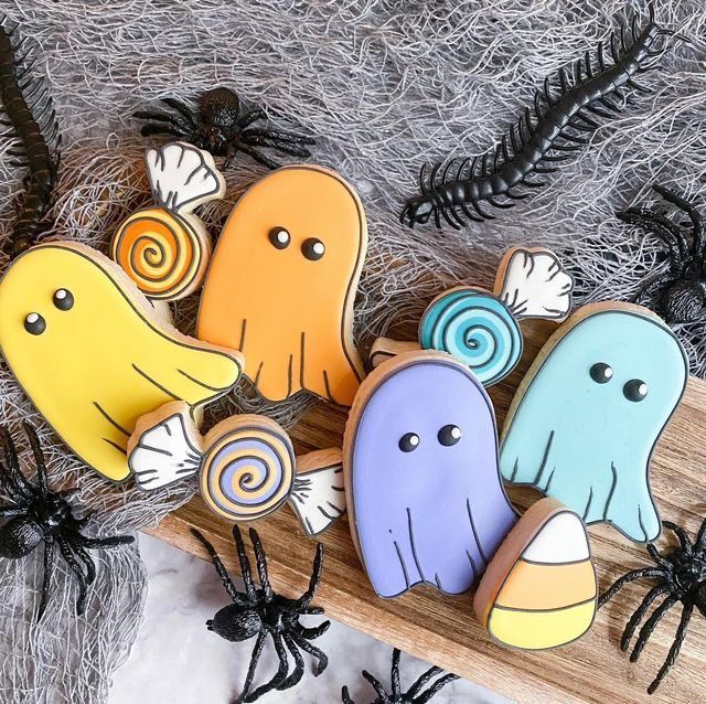 some cookies are decorated to look like ghostes and spider webs on a wooden board