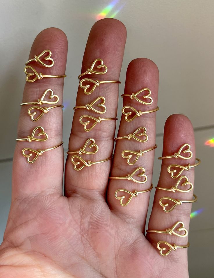 a person holding out their hand with five rings in the shape of hearts on it