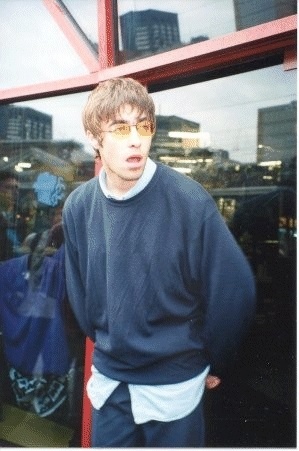 a young man standing in front of a window with his mouth open and wearing glasses