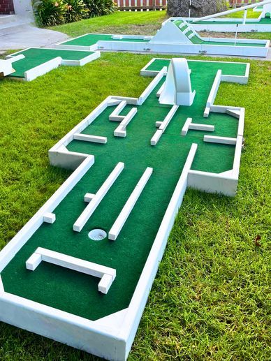 a miniature golf course in the grass with several holes and tees laid out on it