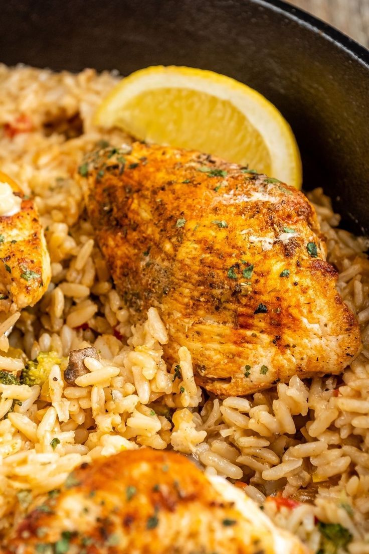 chicken and rice in a skillet with lemon wedges