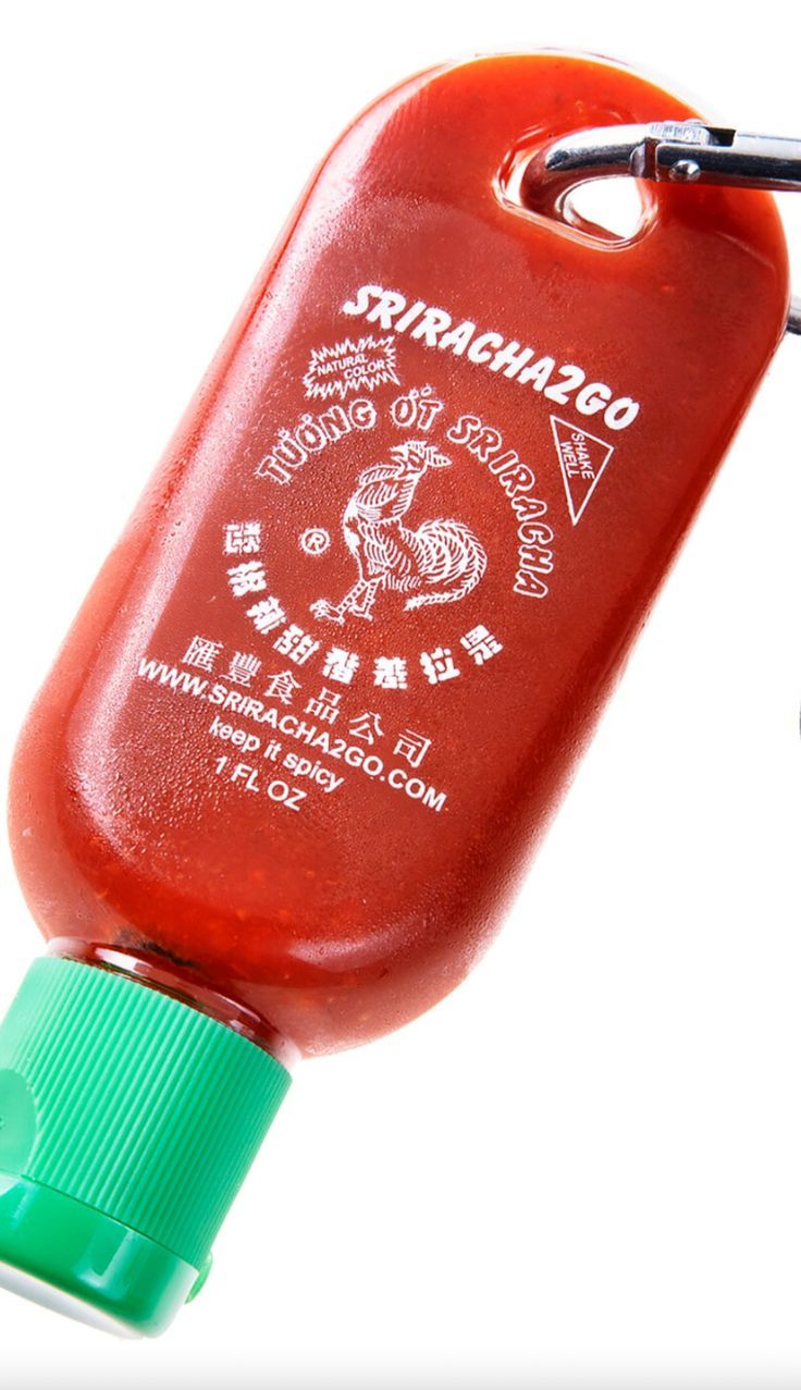 a red bottle with a green cap is hanging from a hook on a white background