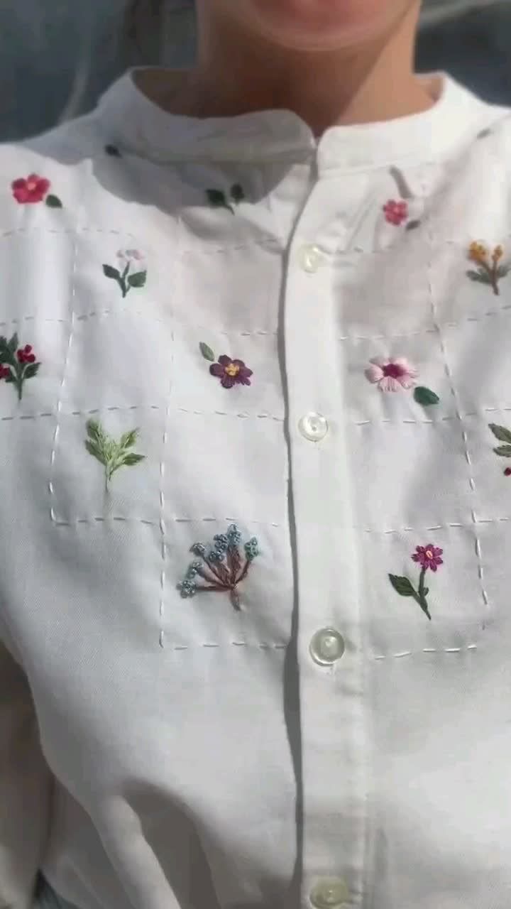 a close up of a person wearing a white shirt with flowers on it and smiling