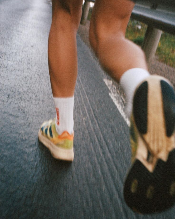 a person wearing tennis shoes and socks walking down the street with their foot on a skateboard