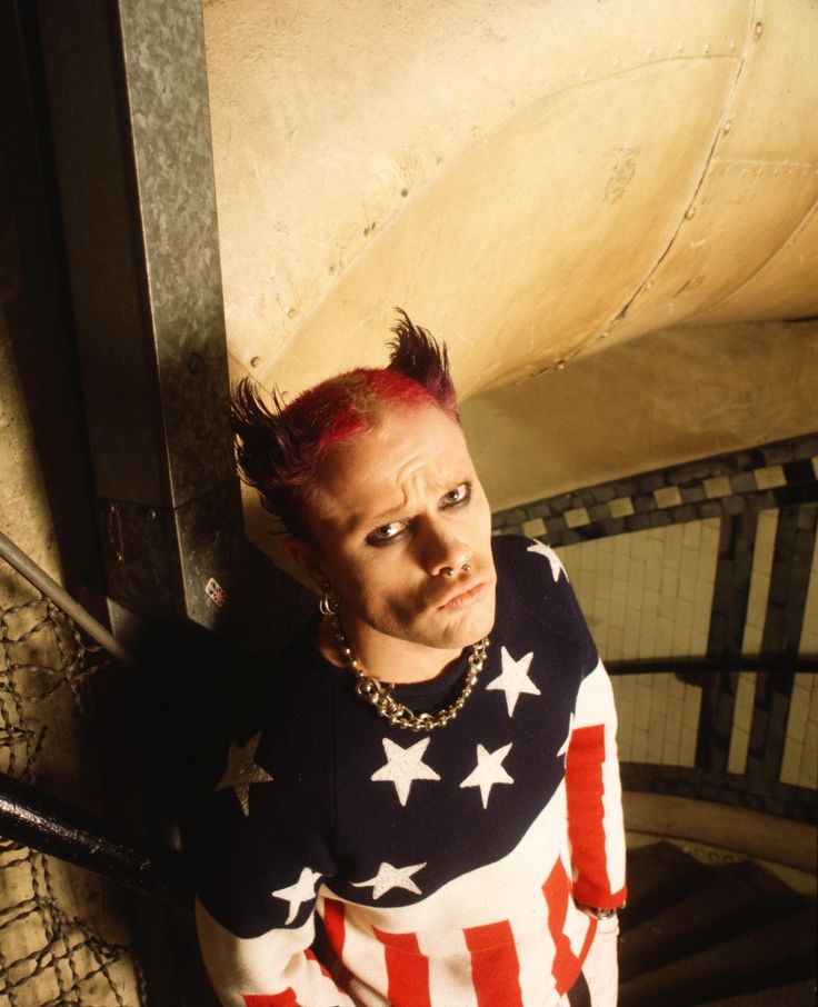 a man with red hair wearing an american flag shirt and gold chain around his neck