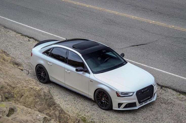 an aerial view of a white car parked on the side of the road next to some rocks