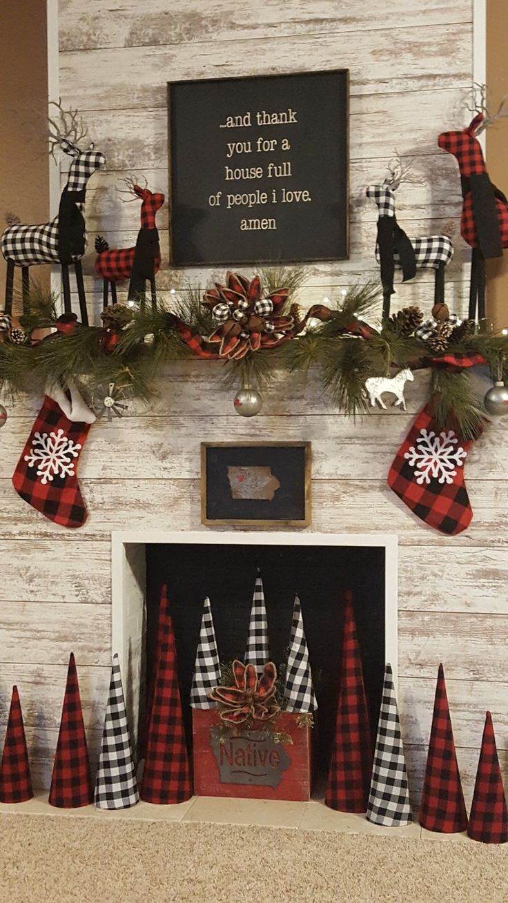 a fireplace decorated for christmas with red and black plaid stocking, deers, snowflakes and pine cones