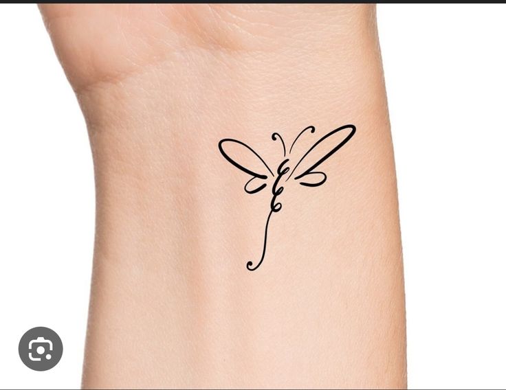 a small tattoo on the wrist of a woman with a dragonfly drawn on it