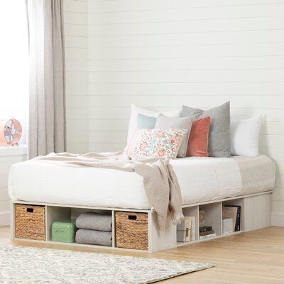 a white bed with drawers underneath it in a room next to a rug and window