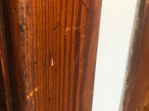 the corner of a wooden door with peeling paint on it