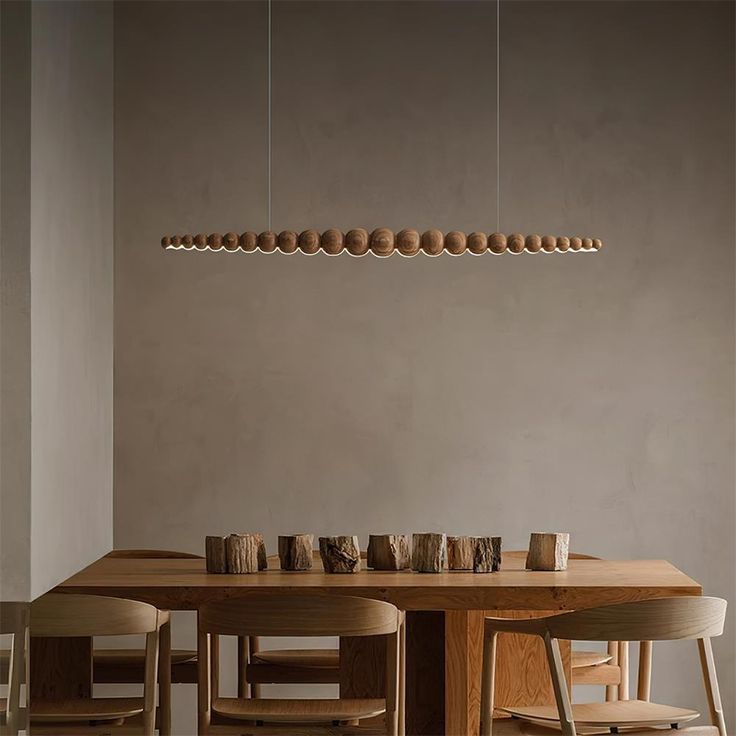 a wooden table with four chairs and a light fixture hanging above it in a dining room