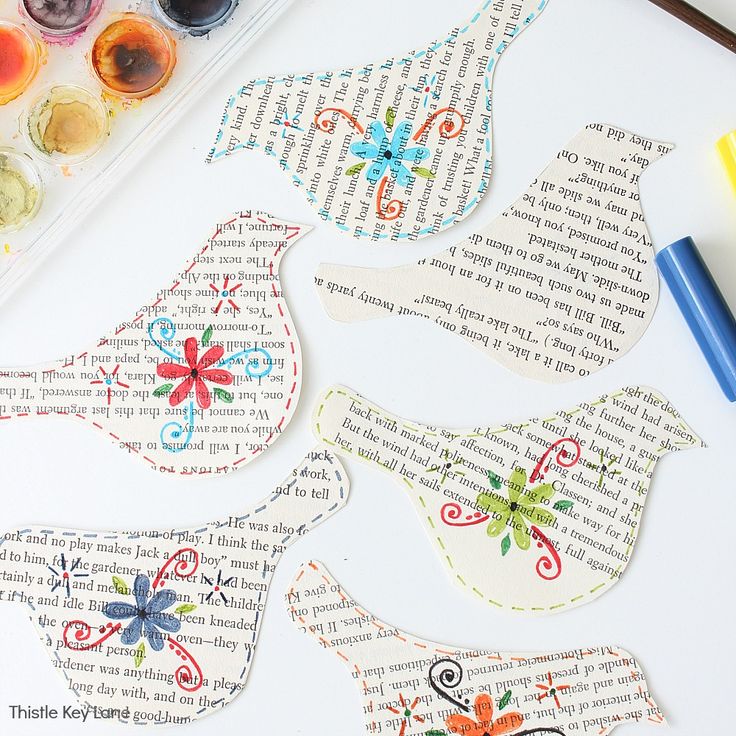 some paper birds are sitting on top of a piece of paper with watercolor paint