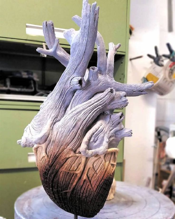 a heart shaped sculpture sitting on top of a wooden table in a room with green cabinets