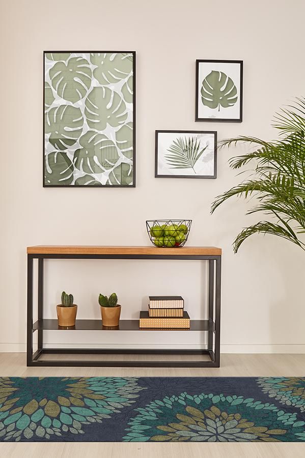 a shelf with some plants and pictures on the wall above it in a living room