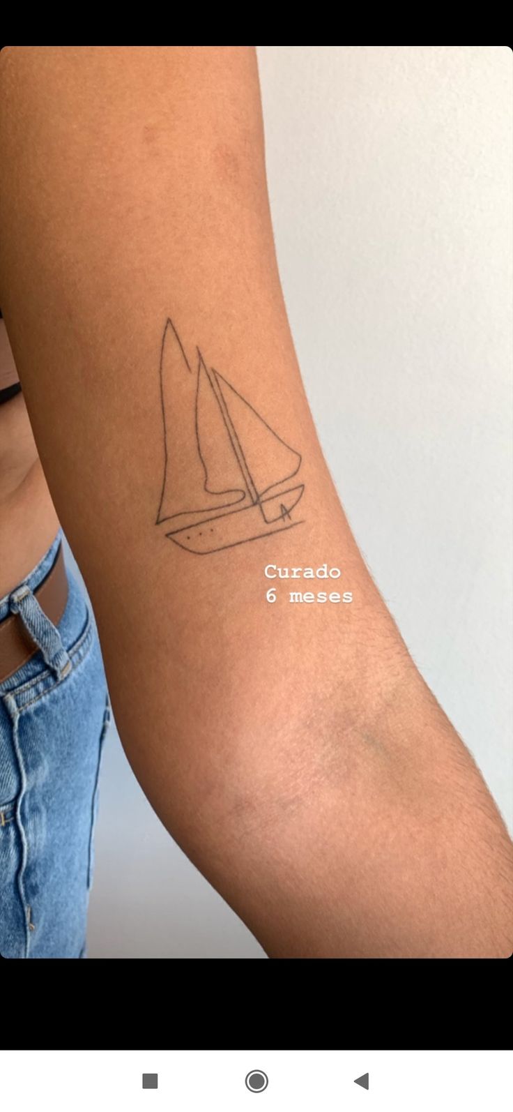 a woman's arm with a tattoo that has a sailboat on the side