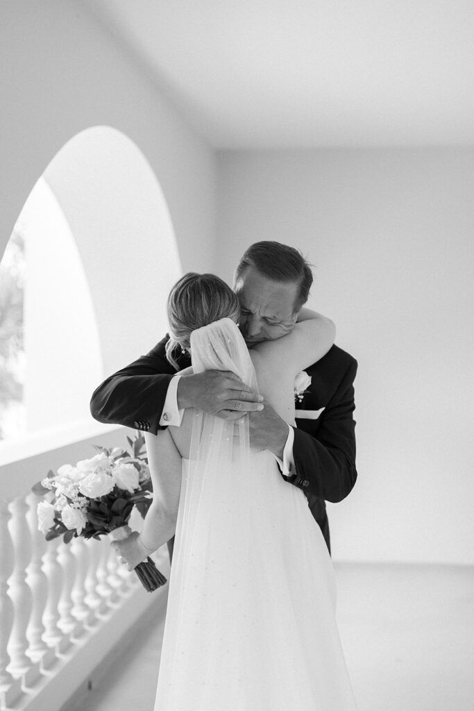 a bride and groom embracing each other on the balcony at their wedding reception in black and white