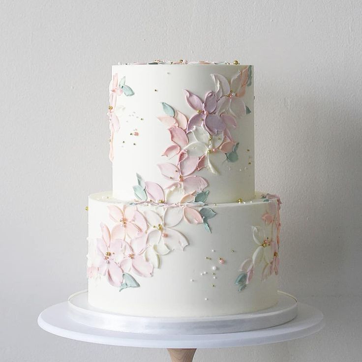 a three layer white cake with pink flowers on it