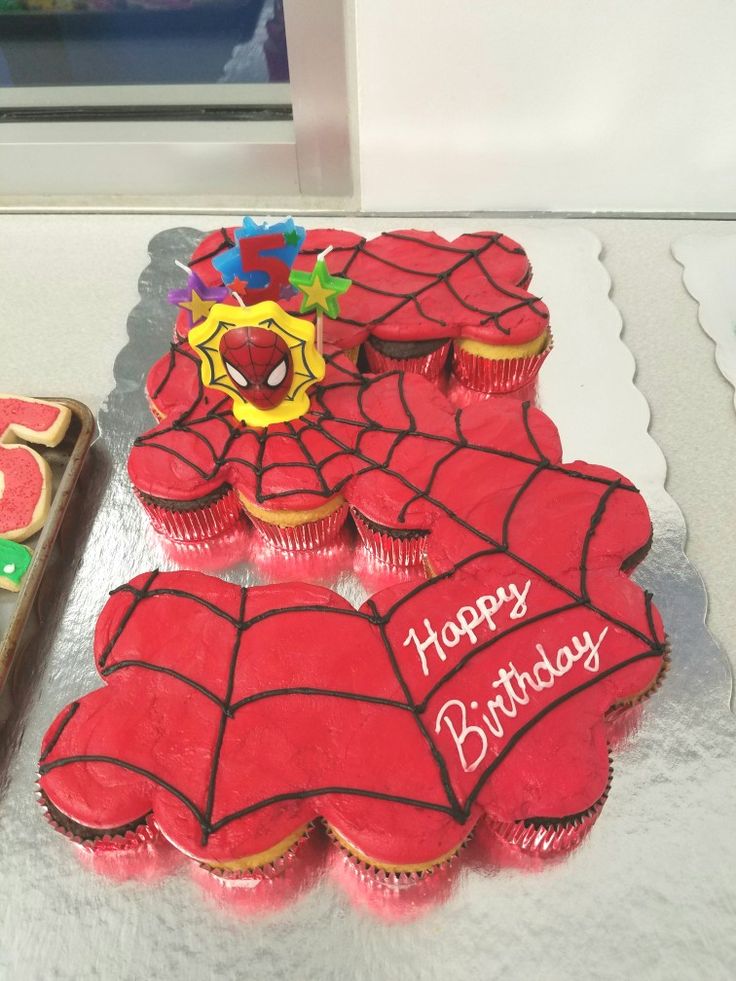 two decorated cupcakes sitting on top of a table next to a box of cookies