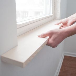 a person's hand reaching for the edge of a window sill