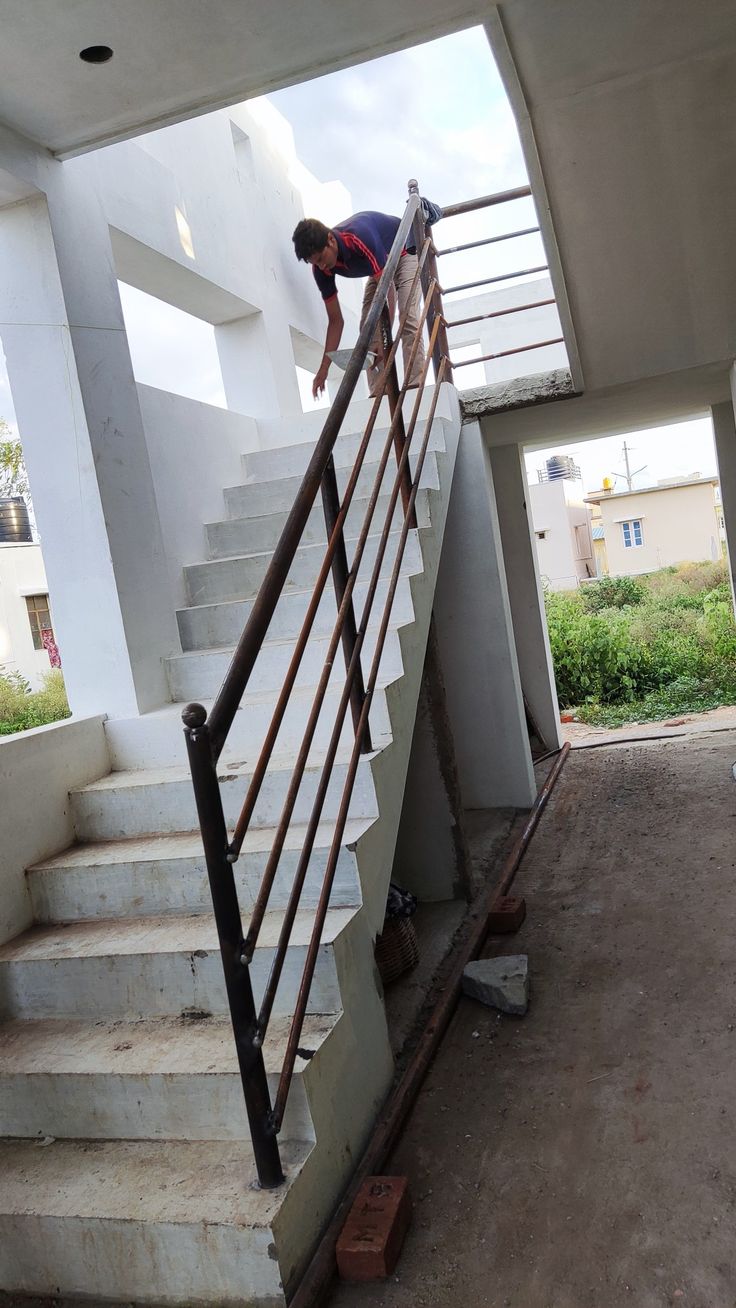 a man climbing up the side of a set of stairs next to a hand rail