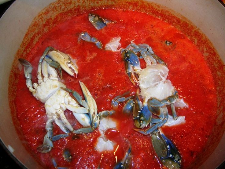 several crabs are cooking in a red sauce