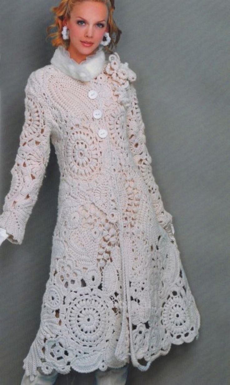 a crocheted doll is posed in a white coat and boots with her hands on her hips