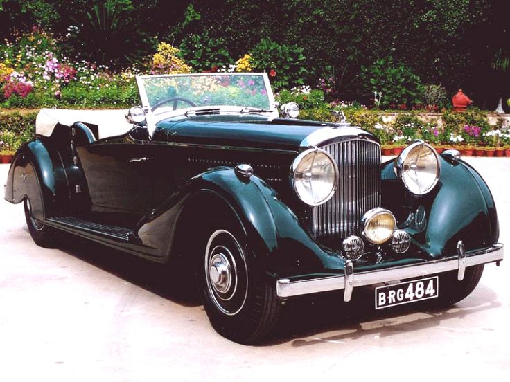 an antique car is parked in front of some flowers