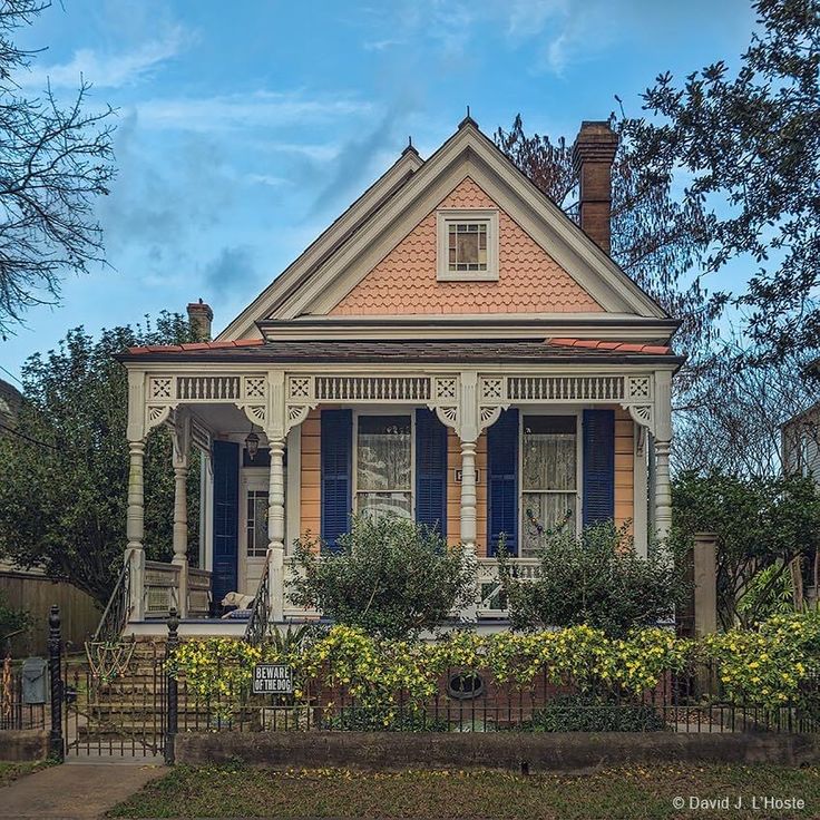 an old house with blue shutters on the front porch and red trim around the windows