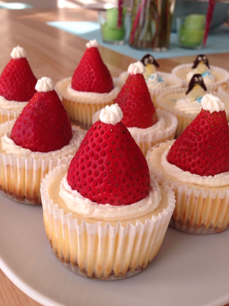 some cupcakes with strawberries on top are sitting on a plate and decorated like santa hats