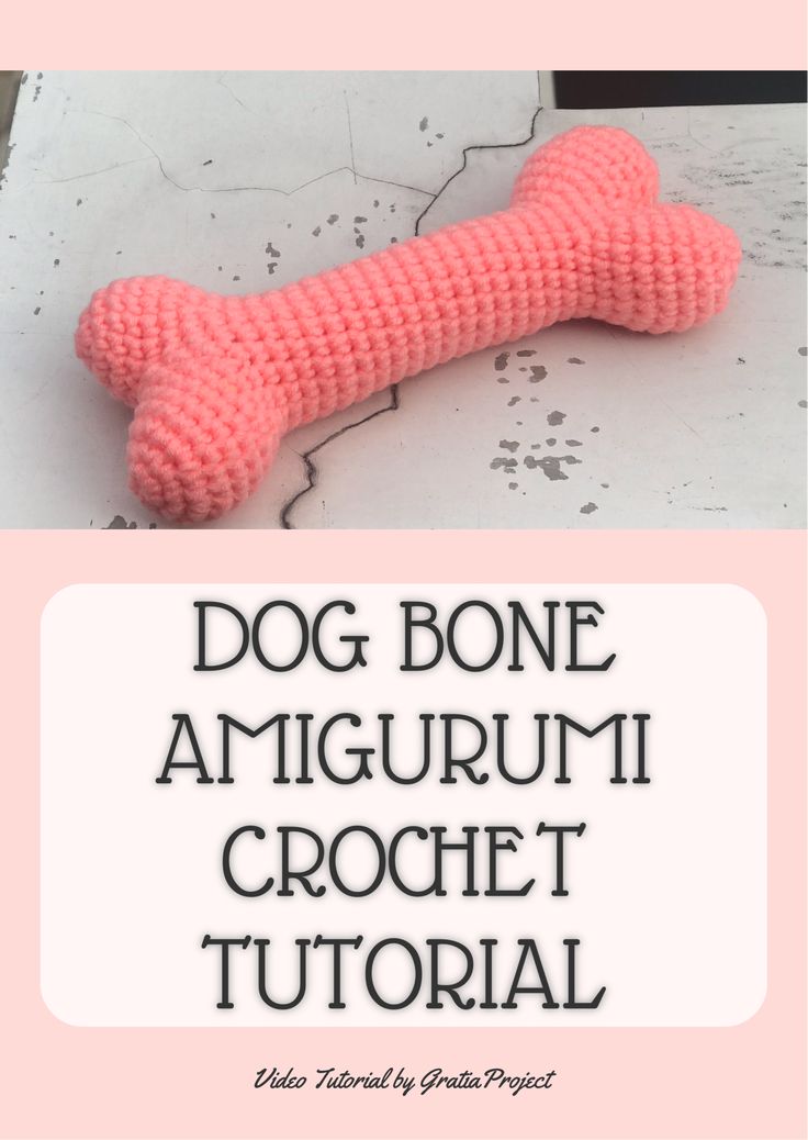 a pink knitted dog bone sitting on top of a white surface with the words, dog bone amigurmi crochet't